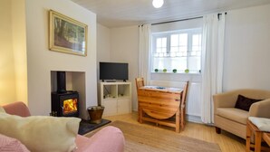 A cozy living room with a fireplace, a television, a dining table, and a sofa. - 2 Bed in Driffield (oc-93141) (Langtoft)