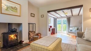 A cozy living room with a fireplace, a sofa, a coffee table, and a view through a glass door to an outdoor area. - 2 Bed in Driffield (oc-93140) (Langtoft)