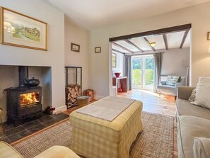 A cozy living room with a fireplace, a sofa, a coffee table, and a view through a glass door to an outdoor area. - 2 Bed in Driffield (oc-93140) (Langtoft)