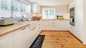 A modern kitchen with white cabinets, a wooden countertop, a toaster, and a black mat with 'TCHEN' on it. - 2 Bed in Driffield (oc-93140) (Langtoft)