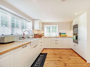 A modern kitchen with white cabinets, a wooden countertop, a toaster, and a black mat with 'TCHEN' on it. - 2 Bed in Driffield (oc-93140) (Langtoft)
