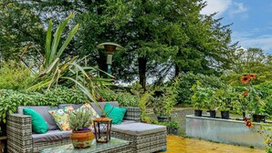 Een terras met rieten meubels, een bloempot en een lamp.