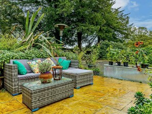 A patio with wicker furniture, a potted plant, and a lamp. - 3 Bed in Stoke-on-trent (oc-92799) (Ipstones)