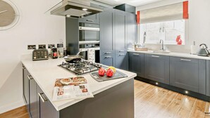 Une cuisine moderne dotée d’un îlot central, d’appareils électroménagers intégrés et d’une fenêtre offrant une vue agréable.