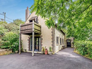 A two-story house with a balcony, a chimney, and a paved driveway. - 3 Bed in Weymouth (oc-92902) (Osmington)