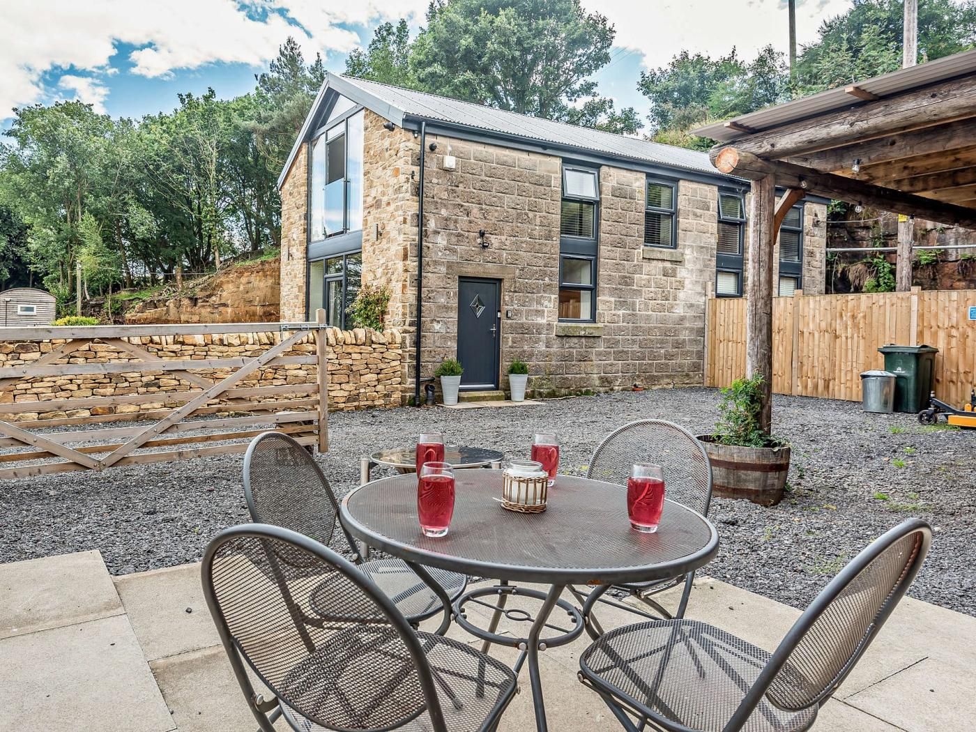 A stone building with a door and windows, surrounded by a gravel area with a table and chairs.