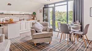 A modern kitchen with a dining area, a sofa, and a table set for two. - 2 Bed in Sheffield (oc-92978) (Upper Midhope)