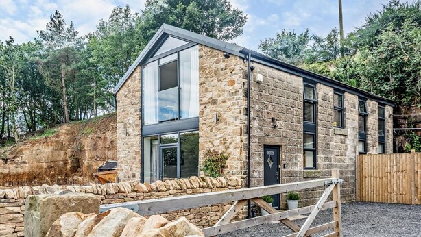 A stone building with a modern design, featuring large windows and a wooden fence. - 2 Bed in Sheffield (oc-92978) (Upper Midhope)