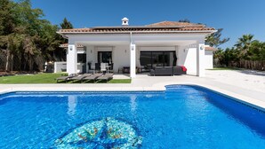 Een modern huis met een zwembad, terras en overdekte patio.