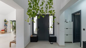 Een modern interieur met een donkere deur, een witte muur en een hangende plant.