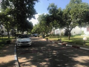 Una calle residencial bordeada de árboles y coches aparcados.