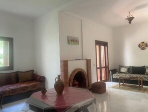 Una sala de estar con chimenea, un sofá, una mesa de centro y una lámpara colgante.
