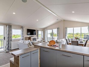 A modern kitchen with a central island, a dining area with a table and chairs, and a television mounted above the island.