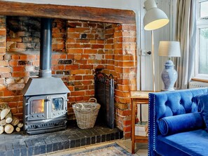 A room with a brick fireplace, a modern stove, a wicker basket, a blue sofa, and a lamp. - 3 Bed in Pershore (oc-92975) (Eckington)