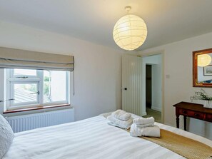 A hotel room with a bed, a bedside table, a lamp, a window with a view, and a door leading to another room. - 3 Bed in Pershore (oc-92975) (Eckington)