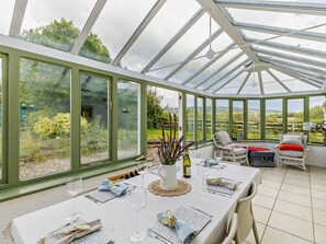 A conservatory with a table set for dining, chairs, and a view of the garden. - 3 Bed in Pershore (oc-92975) (Eckington)