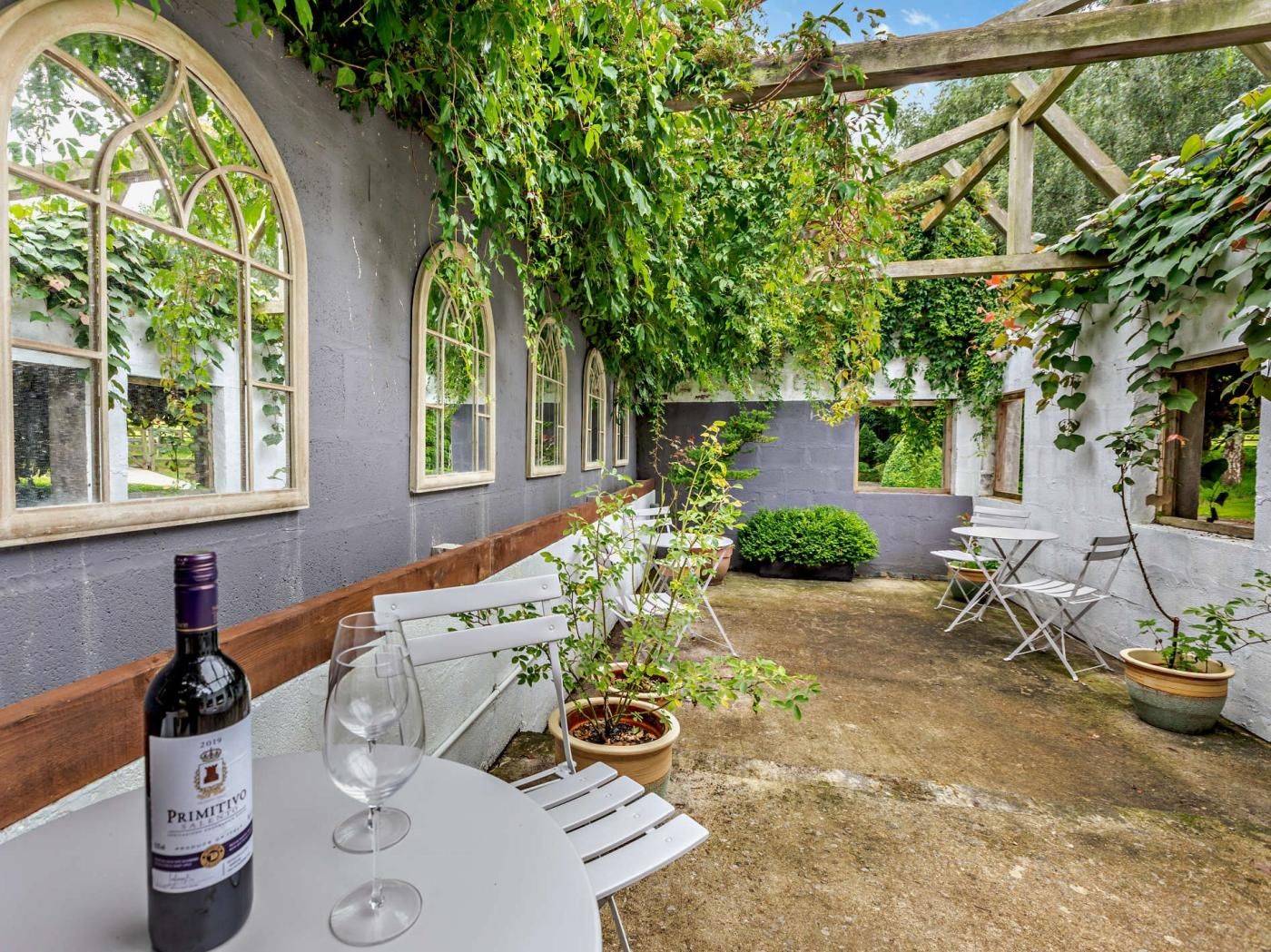 A patio with a table, chairs, and a bottle of wine.