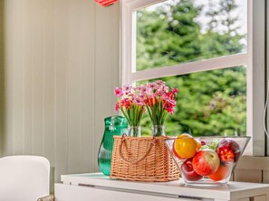 A table with a wicker basket, a green vase, and a glass bowl containing fruits. - 1 Bed in Paignton (oc-93063) (Marldon)
