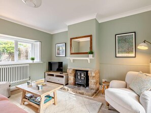 Ein gemütliches Wohnzimmer mit Kamin, Fernseher und einer bequemen Couch.