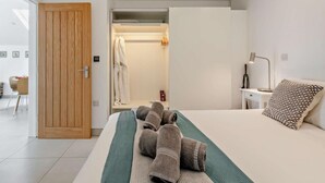 A hotel room with a bed, a bedside table with a lamp, a wooden door, and a bathroom visible through an open door. - 1 Bed in Paignton (oc-93061) (Marldon)
