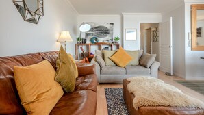 Een woonkamer met een bruine leren bank, een grijze bank en een kamerkleed met dessin.