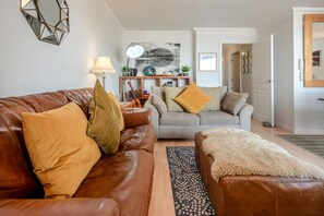 Ein Wohnzimmer mit einem braunen Ledersofa, einem grauen Sofa und einem gemusterten Teppich.