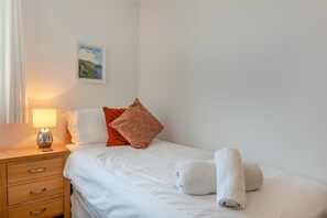 Ein Hotelzimmer mit einem Bett, einem Nachttisch mit Lampe, einem Kopfkissen, einem Handtuch und einem Wandbild.