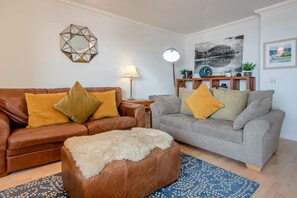 Ein Wohnzimmer mit zwei Sofas, einem Couchtisch, einer Lampe und einem Bild an der Wand.