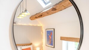Une chambre à coucher avec un lit, une lampe de chevet, un tableau encadré et une fenêtre.