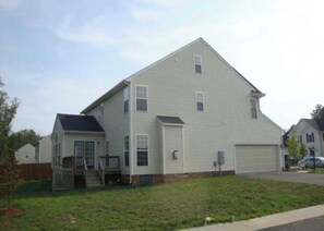 Une maison d’habitation à deux étages, dotée d’un garage, d’un petit porche à l’avant et d’une cour clôturée.