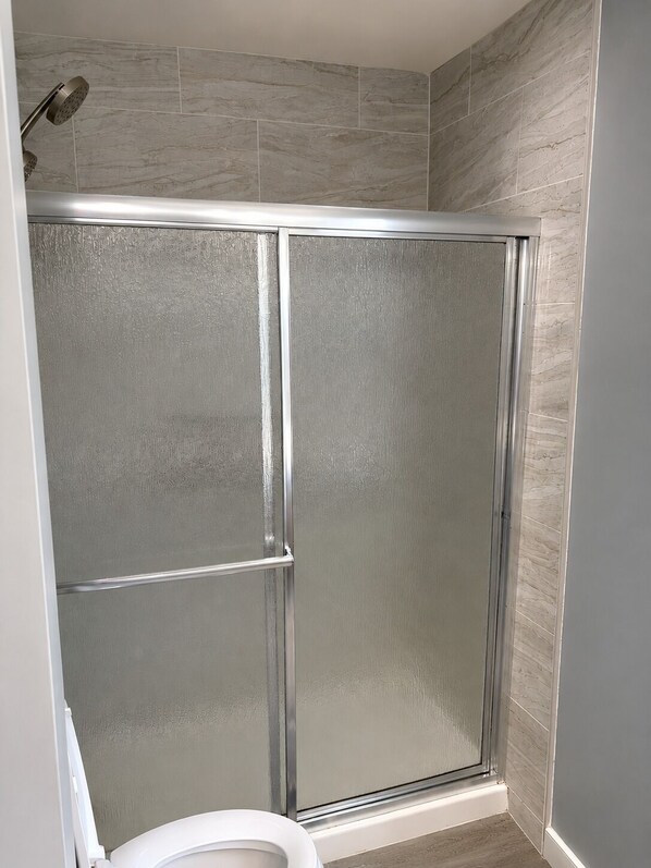 A shower enclosure with a glass door and a showerhead.