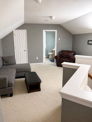 A living room with a grey sofa, a brown leather chair, a white bench, and a white console table.