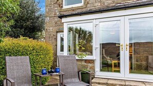 Eine Terrasse mit zwei Stühlen, einem Tisch und einem Fernglas.