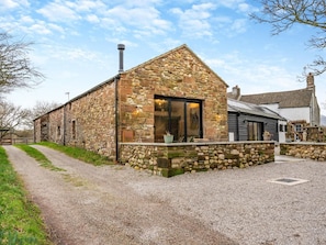 A stone building with a sloped roof, a gravel driveway, and a clear sky. - 2 Bed in Cleator (oc-93196) (Ennerdale and Kinniside)