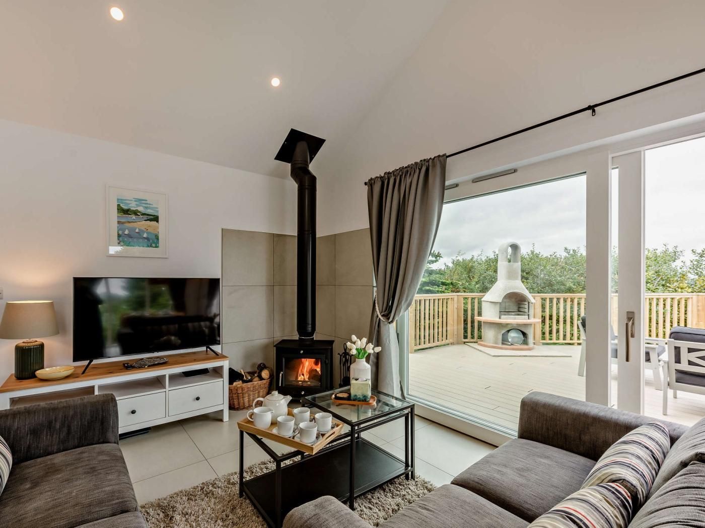 Een moderne woonkamer met een open haard, een televisie en uitzicht op een terras.