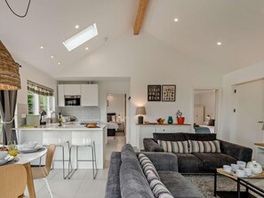 A modern kitchen with white cabinets, a central island, and a dining area with chairs and a table. - 2 Bed in Paignton (oc-93062) (Marldon)