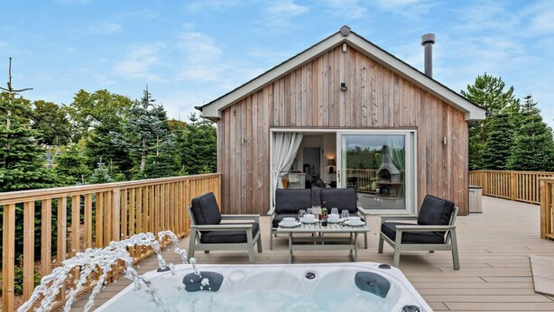 A wooden cabin with a hot tub, outdoor seating, and a deck. - 2 Bed in Paignton (oc-93062) (Marldon)