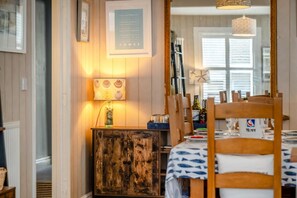 A dining area with a wooden table, chairs, a lamp, and a framed menu on the wall. - 3 Bed in Cowes (oc-92719) (Cowes)