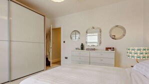 Een slaapkamer met een bed, een kaptafel, een spiegel en een lamp.