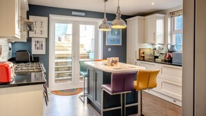 Een moderne keuken met een centraal eiland, barstoelen en uitzicht op buiten.