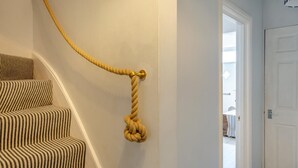 Een trap met een gestreept tapijt en een touw aan de muur.