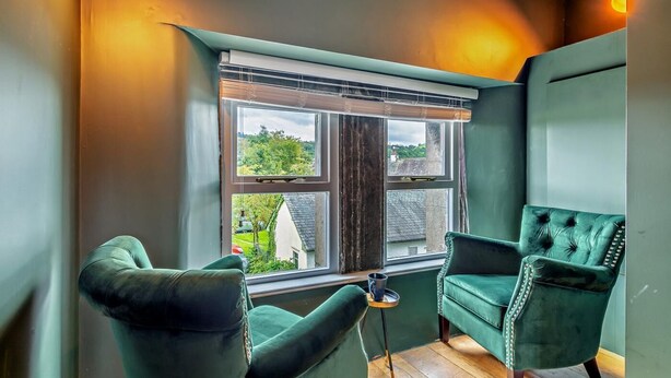 A room with a large window, two green armchairs, a small table, and a wooden floor. - 2 Bed in Ambleside (oc-93167) (Hawkshead)