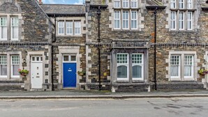 A stone building with a blue door, multiple windows, and a street in front. - 2 Bed in Ambleside (oc-93167) (Hawkshead)