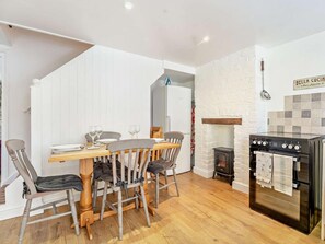Eine moderne Küche mit Esstisch, Stühlen, Herd und Kamin.