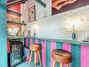Eine Bar mit einer weißen Ziegelwand, Holzstühlen und einem Flaschenregal.
