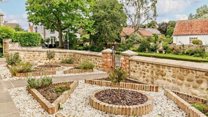 A garden with stone walls, a paved path, and various plants. - 2 Bed in Harrogate (oc-92721) (Bishop Monkton)