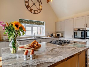 A modern kitchen with a large island, a clock, and a window with a view. - 2 Bed in Harrogate (oc-92721) (Bishop Monkton)