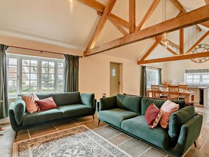 A spacious living room with two green sofas, a patterned rug, and a wooden ceiling structure. - 2 Bed in Harrogate (oc-92721) (Bishop Monkton)