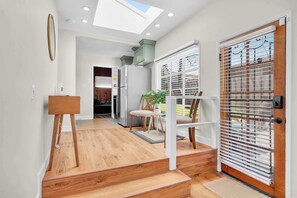 A modern kitchen with a skylight, wooden flooring, and a dining area with a table and chairs. - Walk to Old Town | Family Retreat w/ Big Backyard! (San Diego)