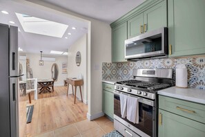 A modern kitchen with green cabinets, a stainless steel stove, and a microwave. - Walk to Old Town | Family Retreat w/ Big Backyard! (San Diego)